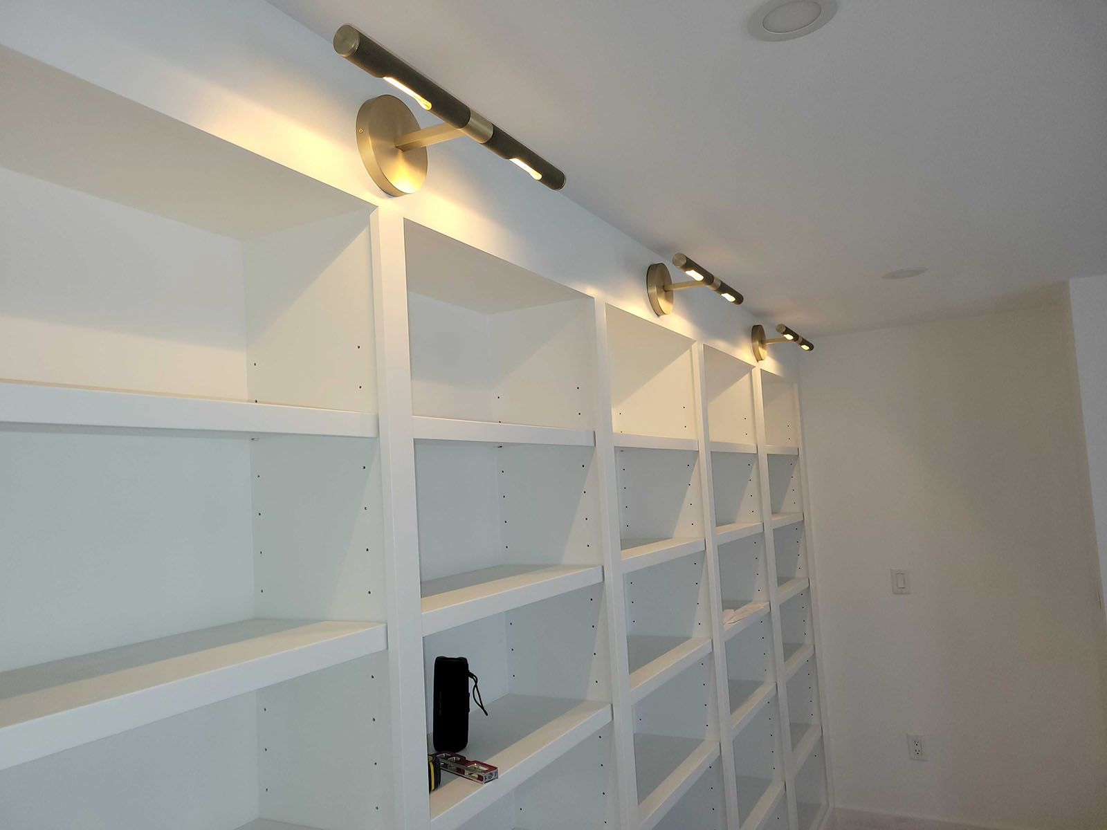 White built-in bookshelves with overhead gold lights