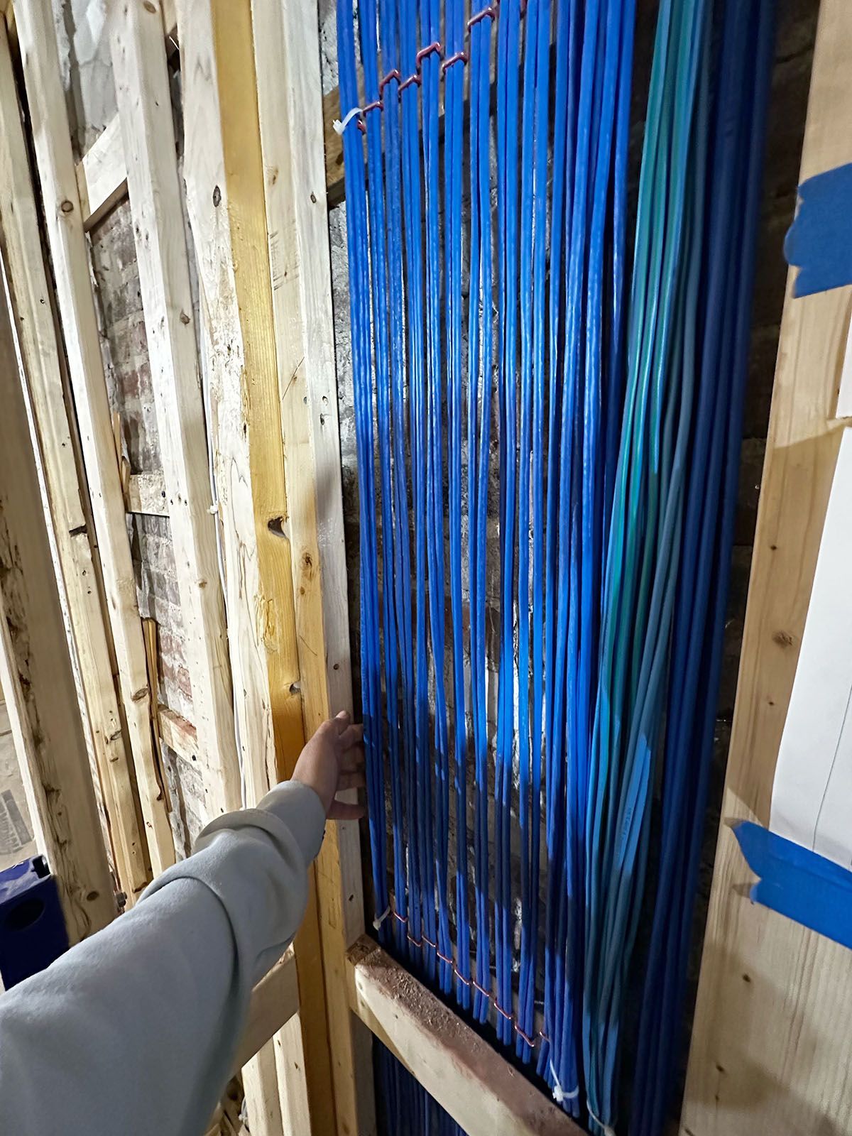 Hand touching a bundle of blue wires in a wooden frame