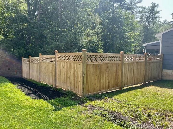 Wooden privacy fence with lattice top in a sunny backyard beside a house and trees