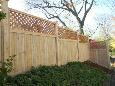 Wooden privacy fence with lattice top along a sloped garden bed in a backyard