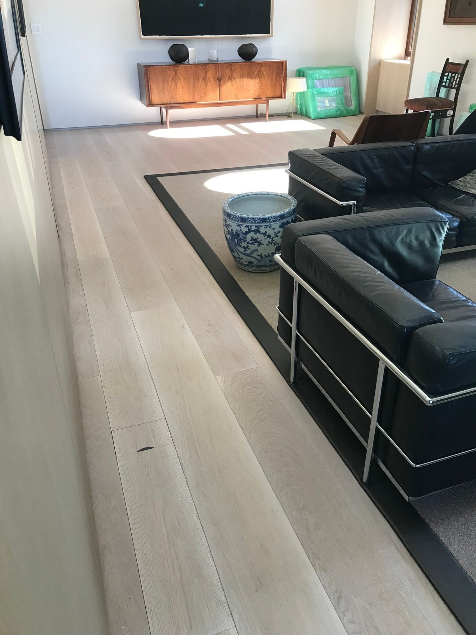 Living room with light wood floors, a rug, and black leather furniture.