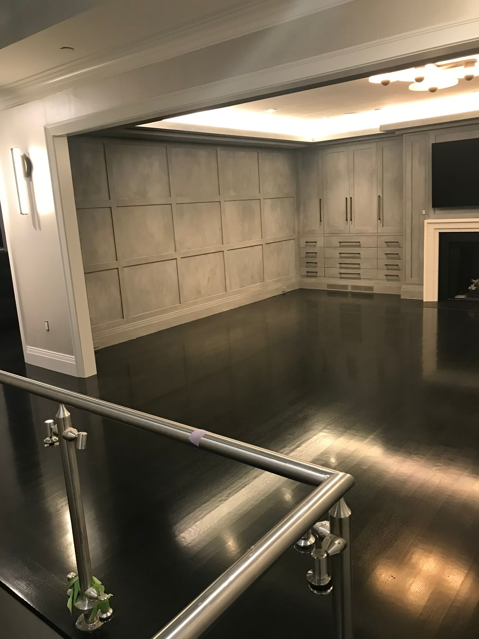Empty room with dark glossy floor, gray paneled walls, and a white fireplace.