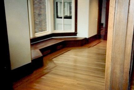 Hardwood floor with a built-in window seat and entryway.