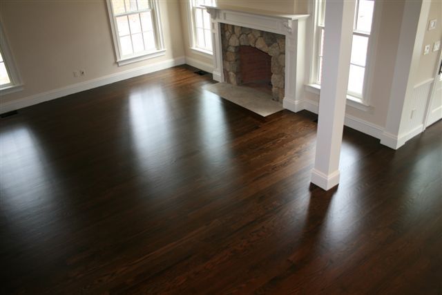 Dark wood floor in a brightly lit living room with a fireplace and white trim.