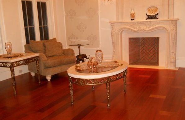 Living room with fireplace, wood floors, furniture, and decorative accents in gold and ivory.
