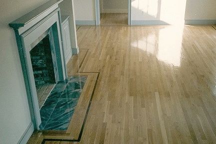 Wooden floor with a fireplace on the left. Dark-trimmed border around a blue-tiled hearth.