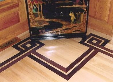 Wooden floor with inlaid geometric design, in front of a decorative cabinet with a painted scene.