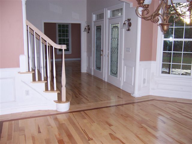 Hardwood floor in home with staircase, double doors with stained glass, and chandelier.