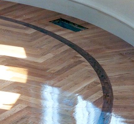 Wooden parquet floor with a dark curved border, vent, and arched ceiling.