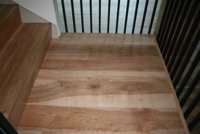 Wooden staircase with a landing and black metal railing.