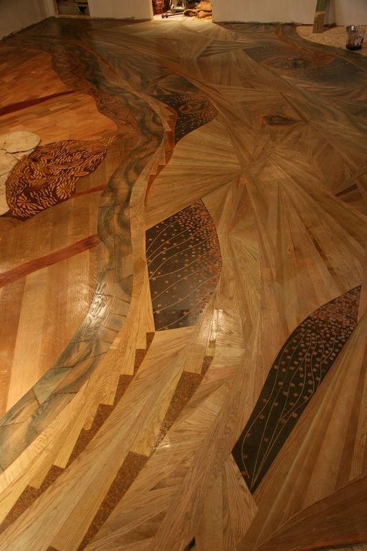 Intricate wooden floor design, geometric shapes with flowing lines in various wood tones.