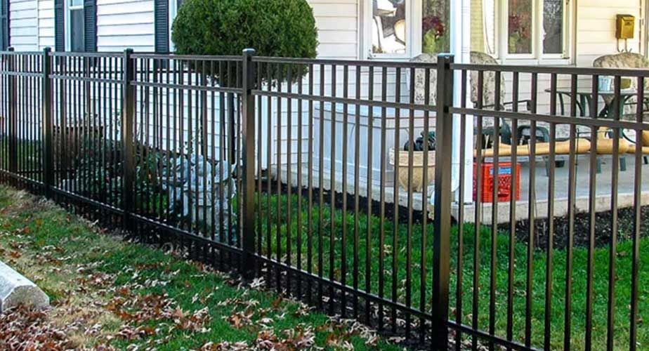 A black metal fence is surrounding a white house.