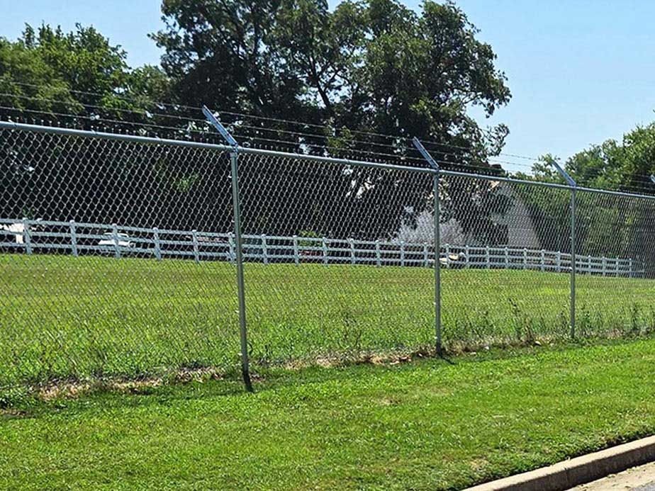A chain link fence surrounds a grassy field