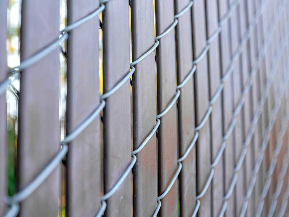 A close up of a chain link fence behind a wooden fence.
