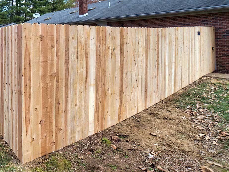 A wooden fence is sitting in front of a brick house.