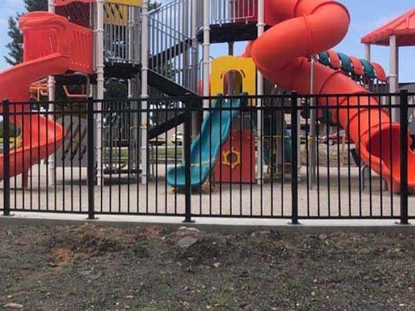 A playground with a slide and stairs behind a fence.