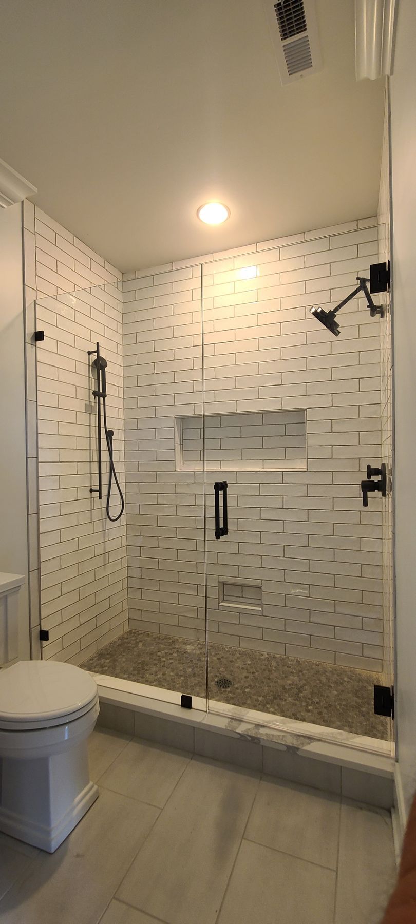 A bathroom with a toilet and a walk in shower with a glass door.