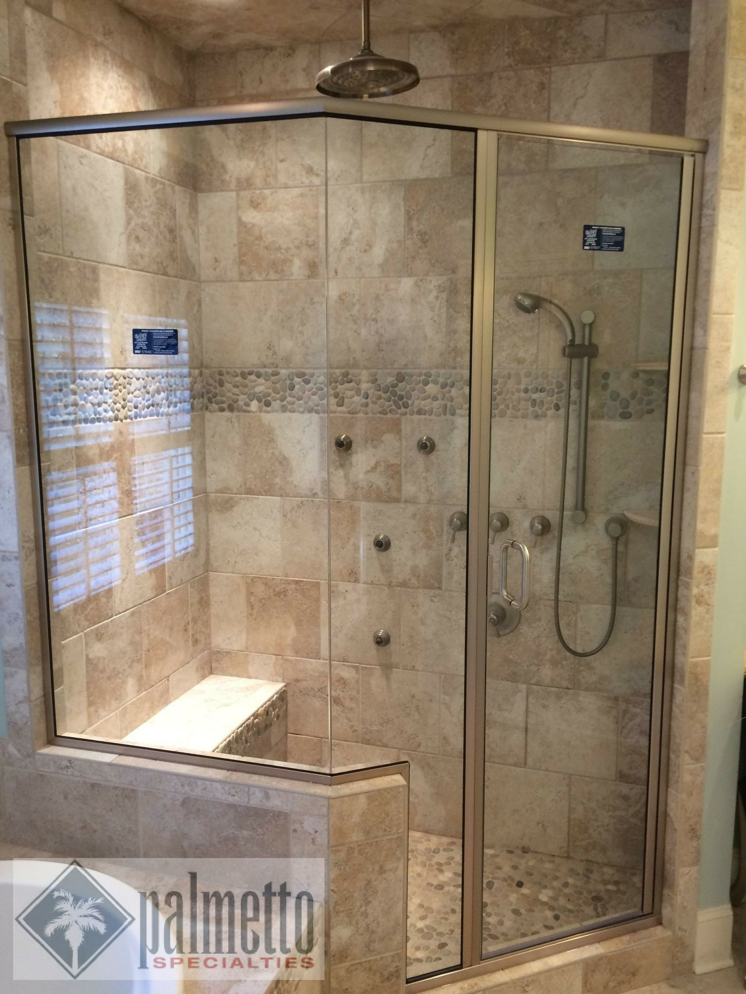 A walk in shower with a sliding glass door and a bench.