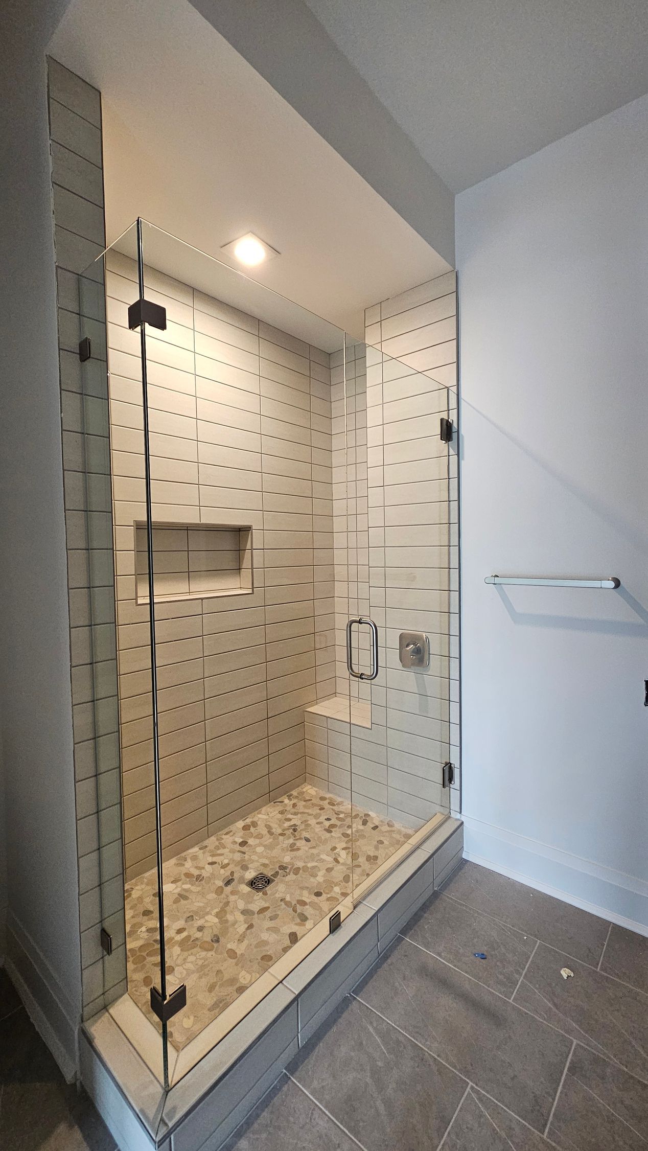 A bathroom with a walk in shower with a glass door.