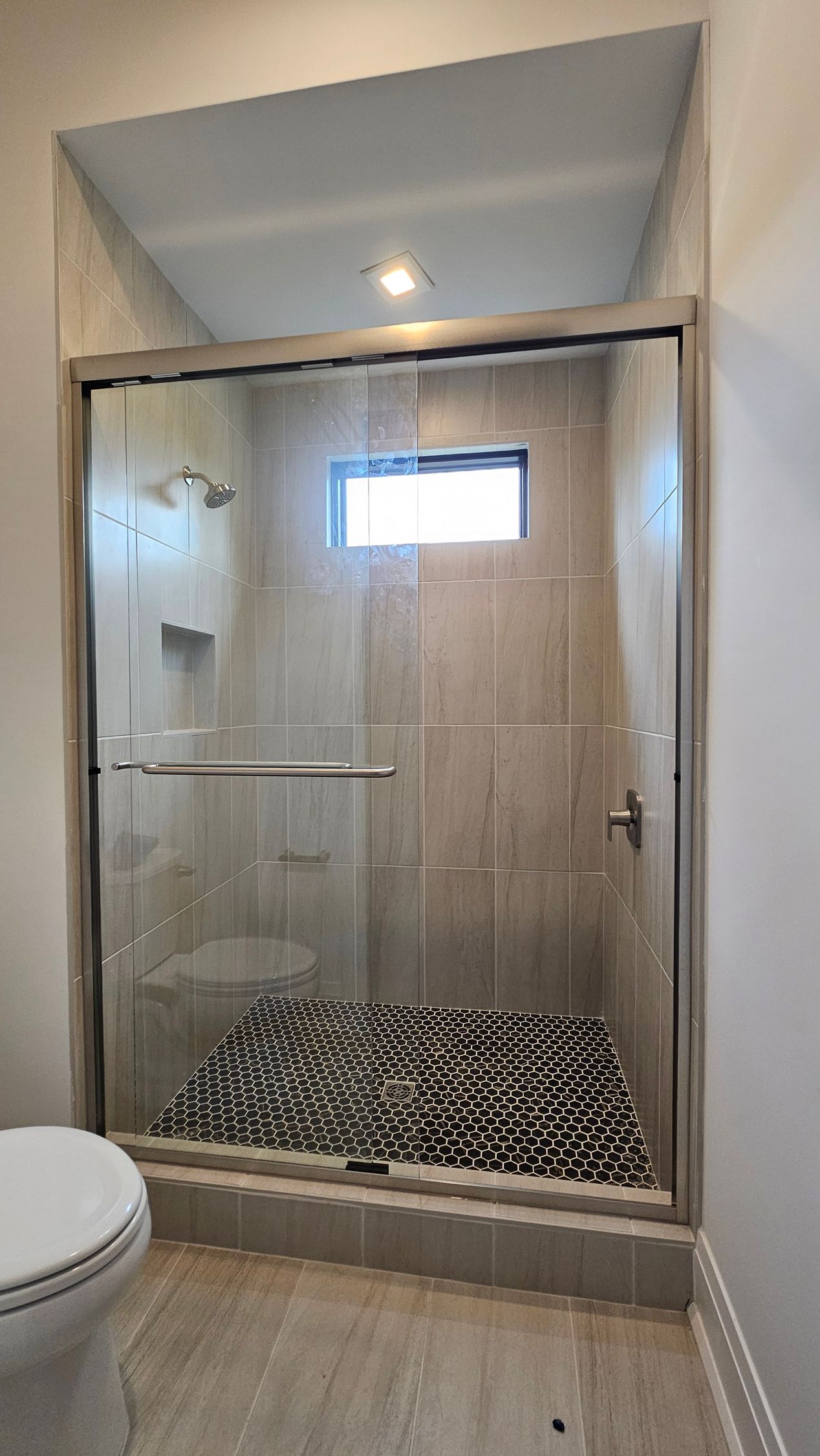 A bathroom with a sliding glass shower door and a toilet.