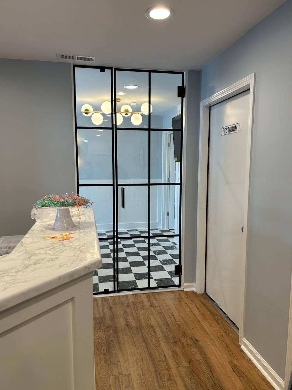 A hallway with a checkered floor and a glass door