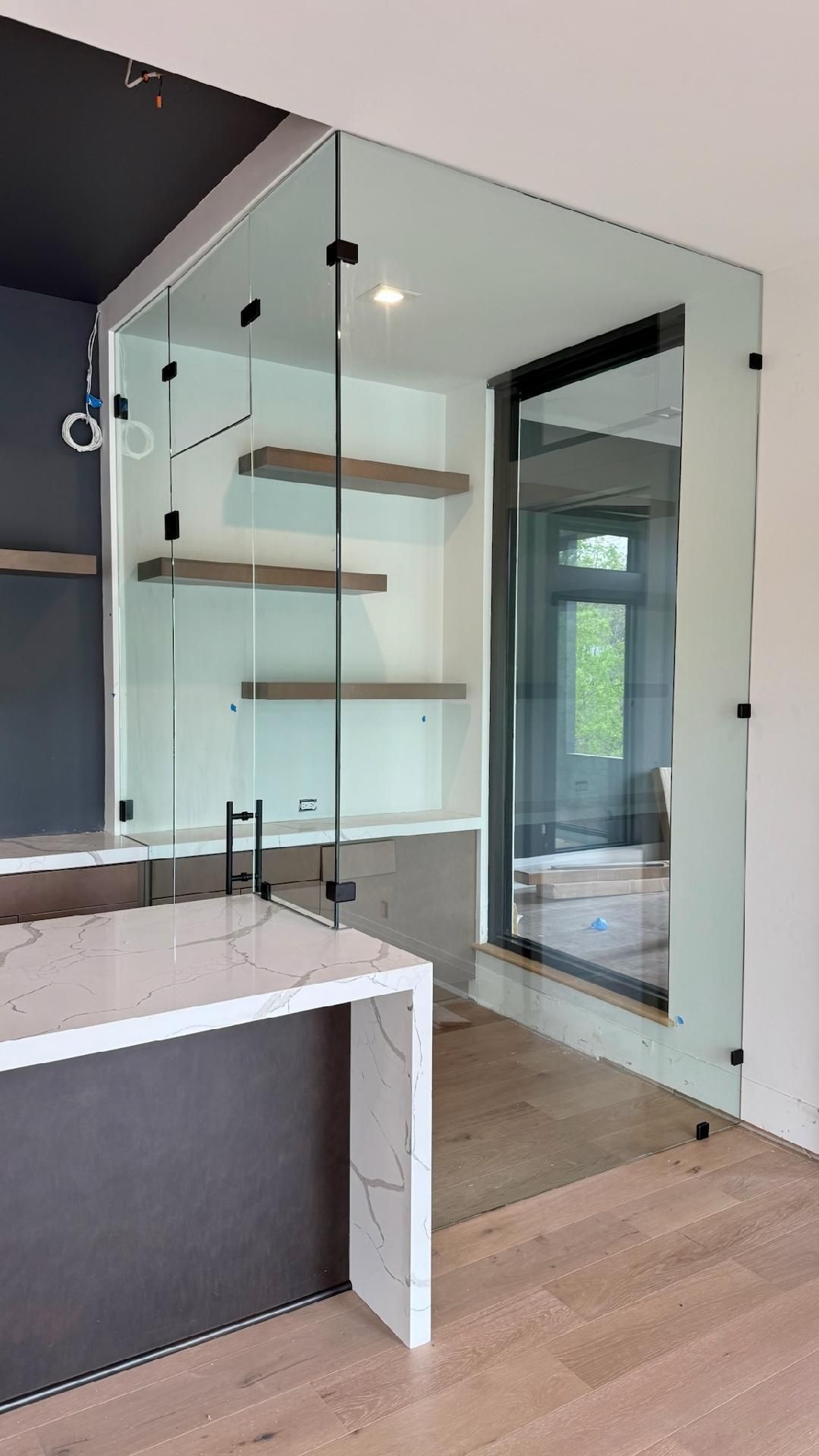 A bathroom with a glass shower door and a marble counter top.