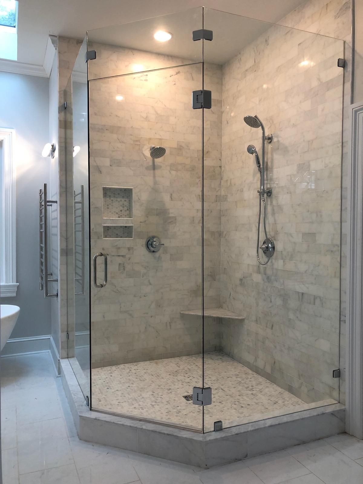 A bathroom with a walk in shower with a glass door.
