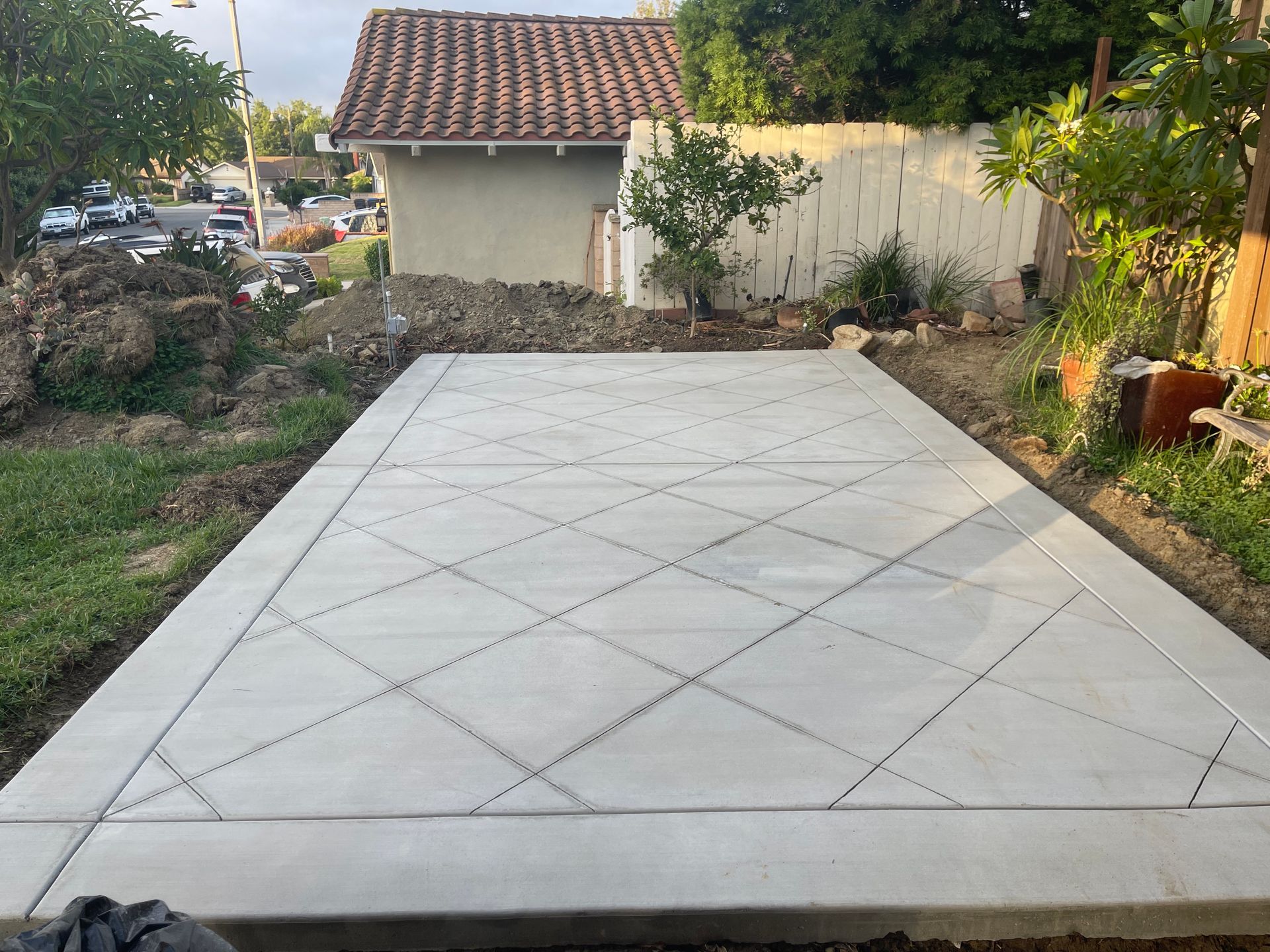 Paved concrete driveway with diamond pattern leading to a small house and garden gate