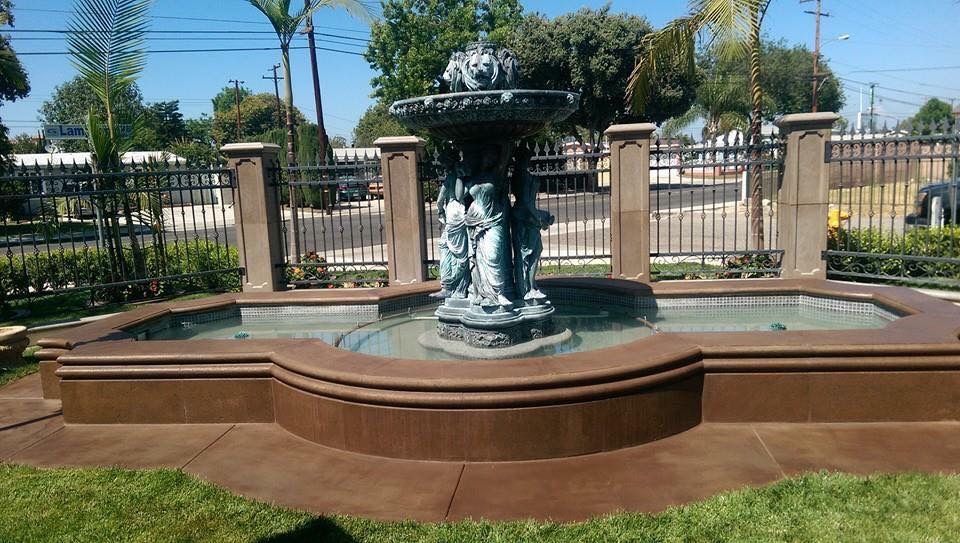 Patio with stamped concrete flooring, covered by a white pergola. The space features columns and glass doors.