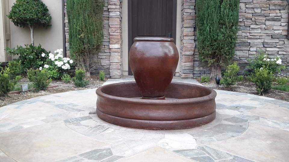 Patio with stamped concrete flooring, covered by a white pergola. The space features columns and glass doors.
