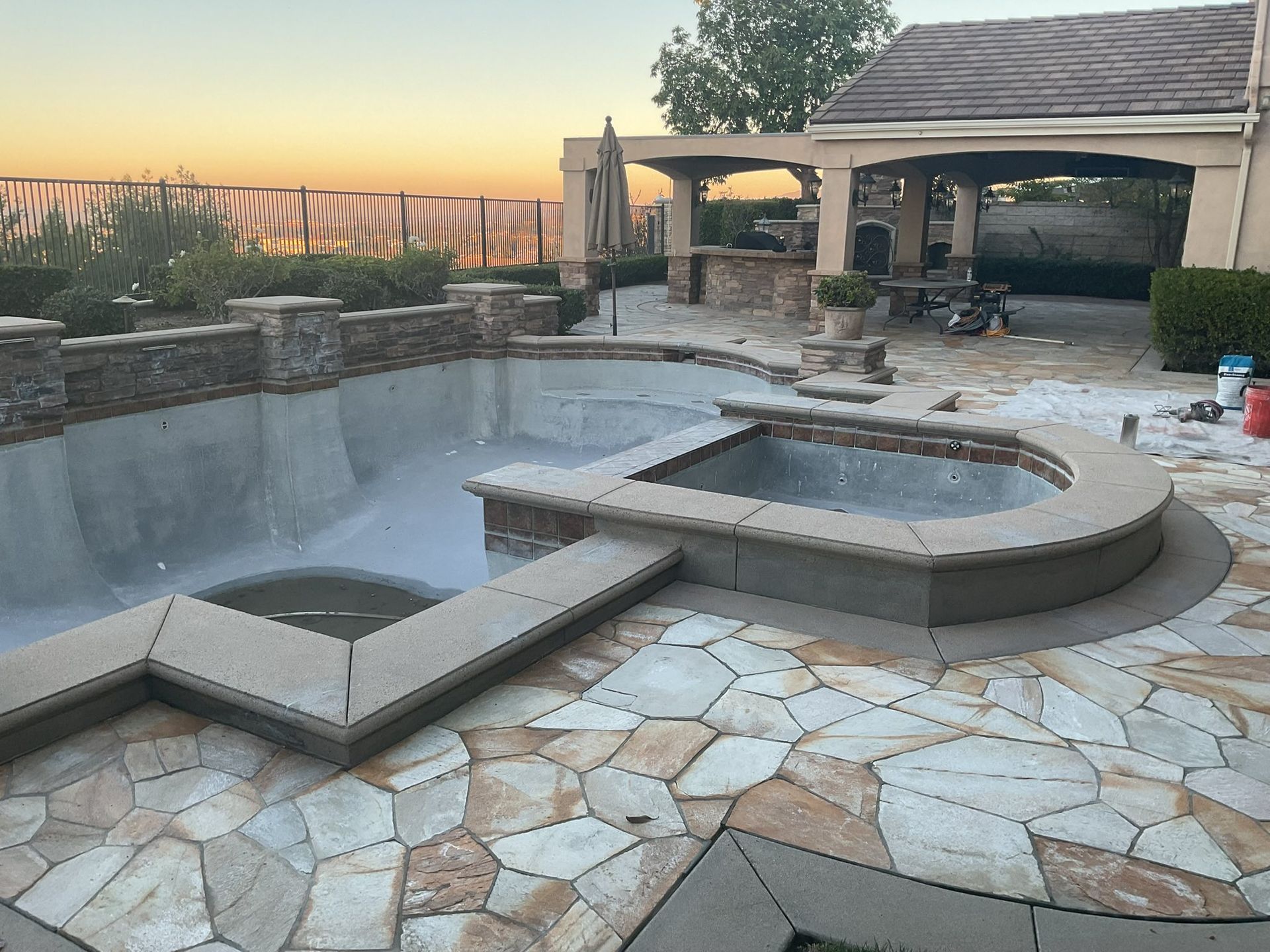 Concrete patio with peeling coating, black railing, and white columns.