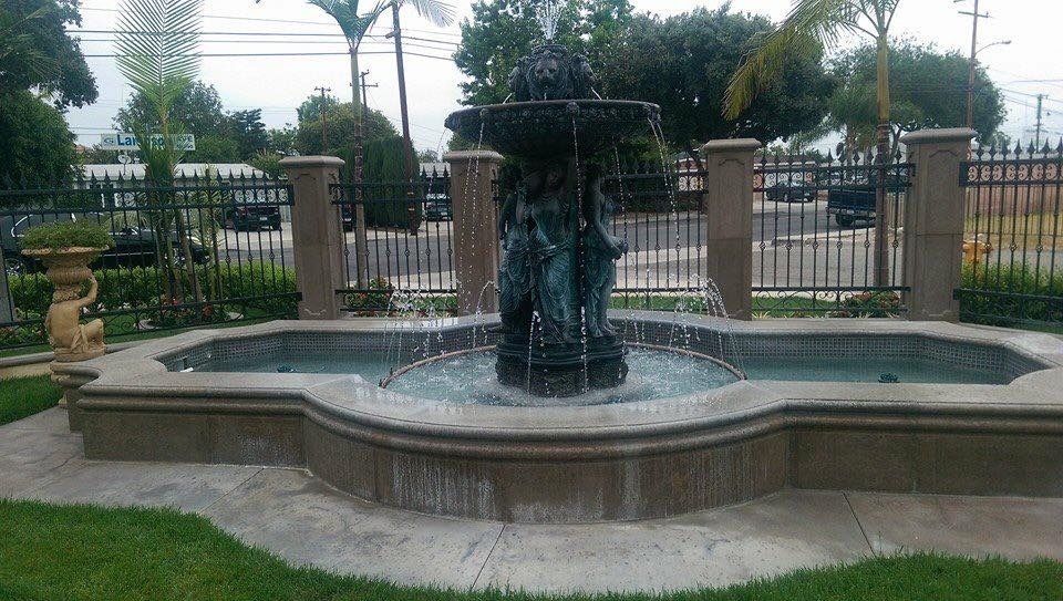 Concrete patio with peeling coating, black railing, and white columns.