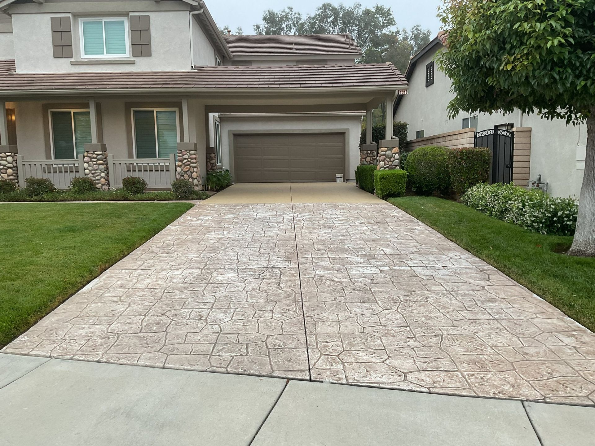 A house with a patterned concrete driveway, green lawn, and garage.