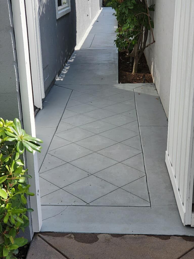 A narrow gray concrete walkway with a decorative diamond pattern.