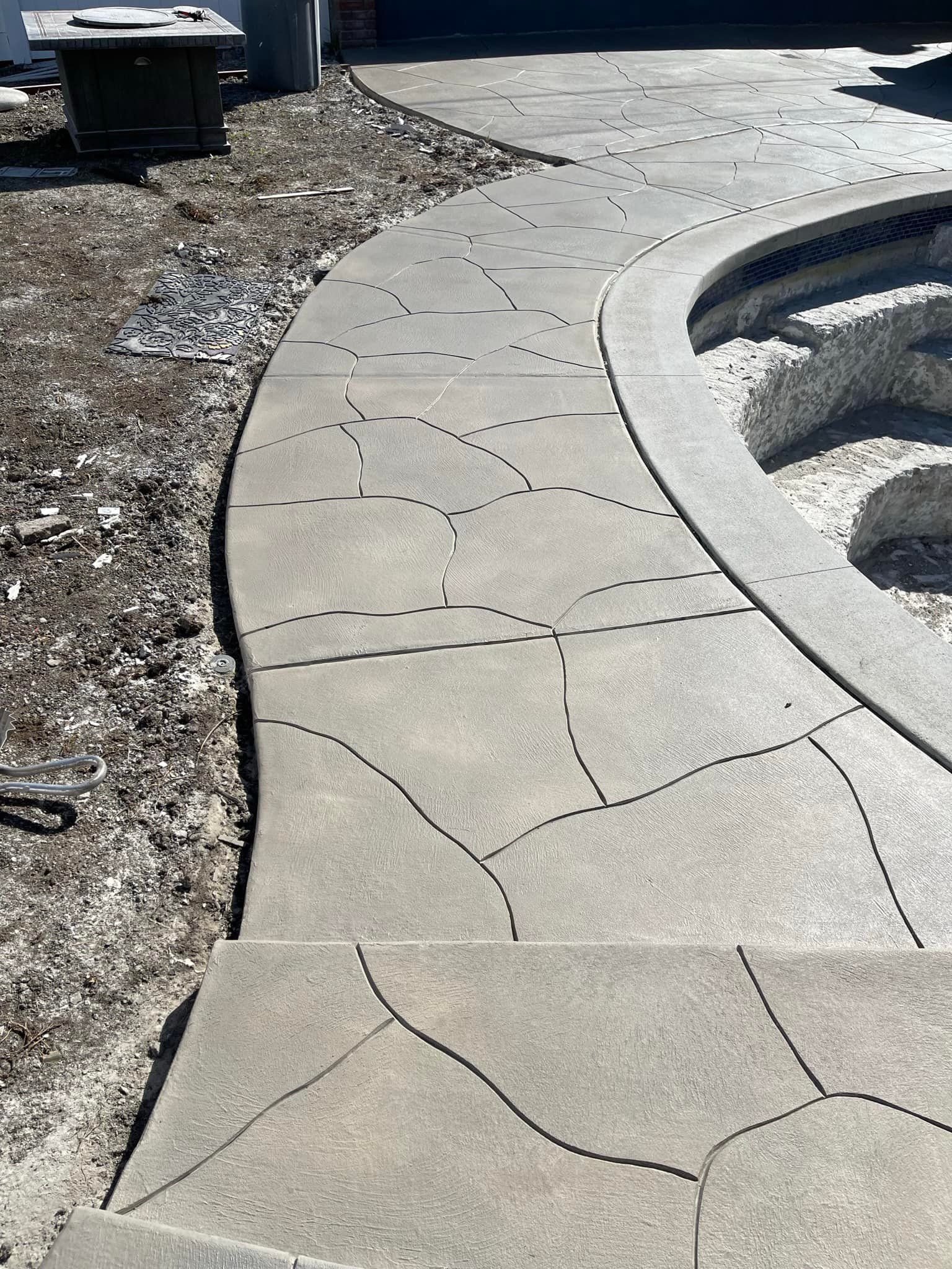 Concrete pathway with decorative cracks leading to a pool area.
