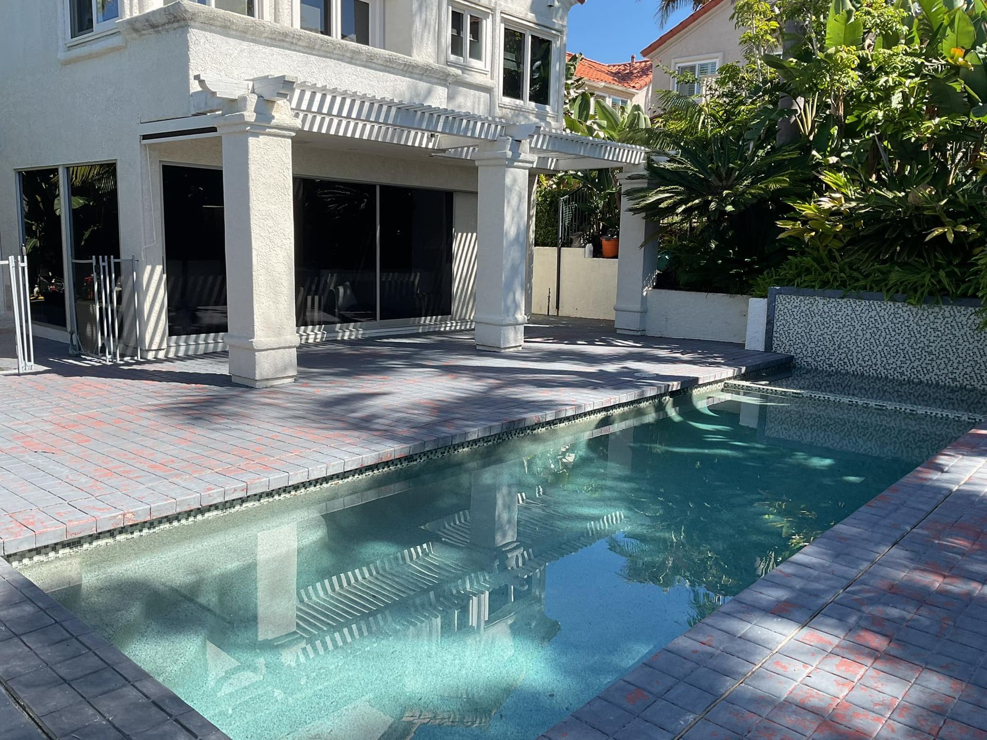 Backyard with pool and house; patio with brick pavers.