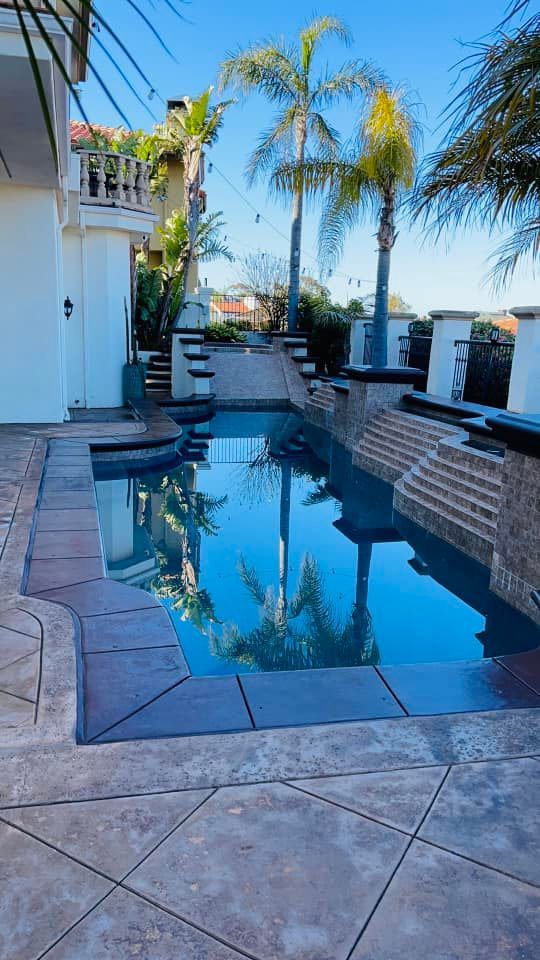 A backyard pool with palm tree reflections.  Steps lead to a higher level.