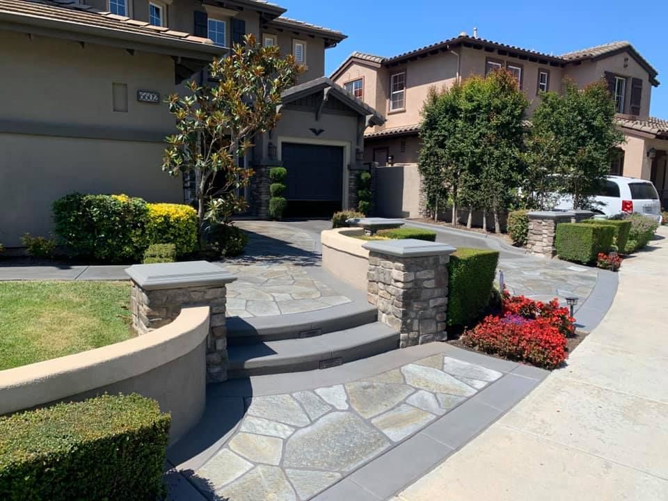 Stone pathway leading to a house with a garage, steps, and landscaped front yard.