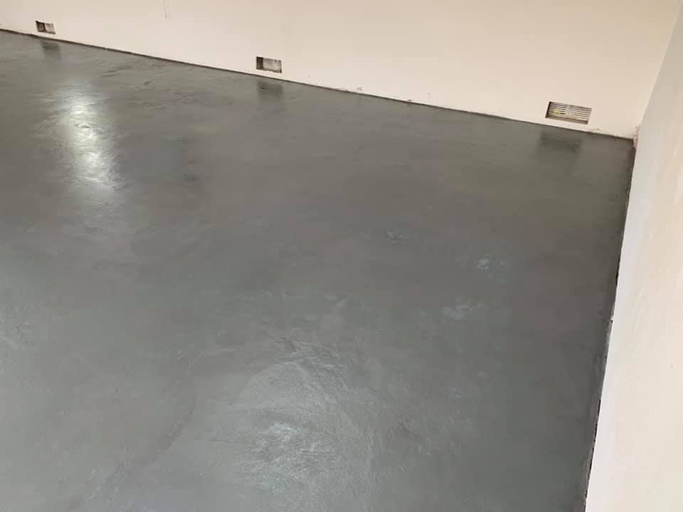 Grey epoxy flooring in an empty room with white walls.