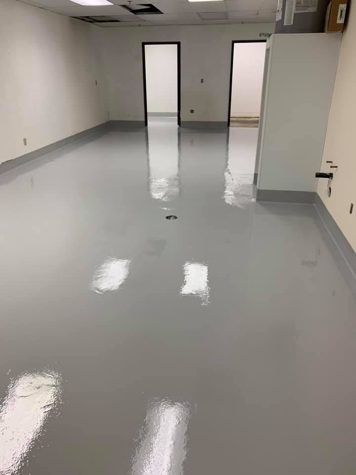 A spacious, empty room with a shiny gray floor, white walls, and three doorways.