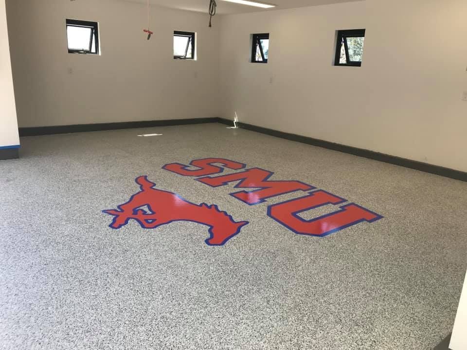Garage floor with SMU logo in red, blue, and white on speckled gray flooring.
