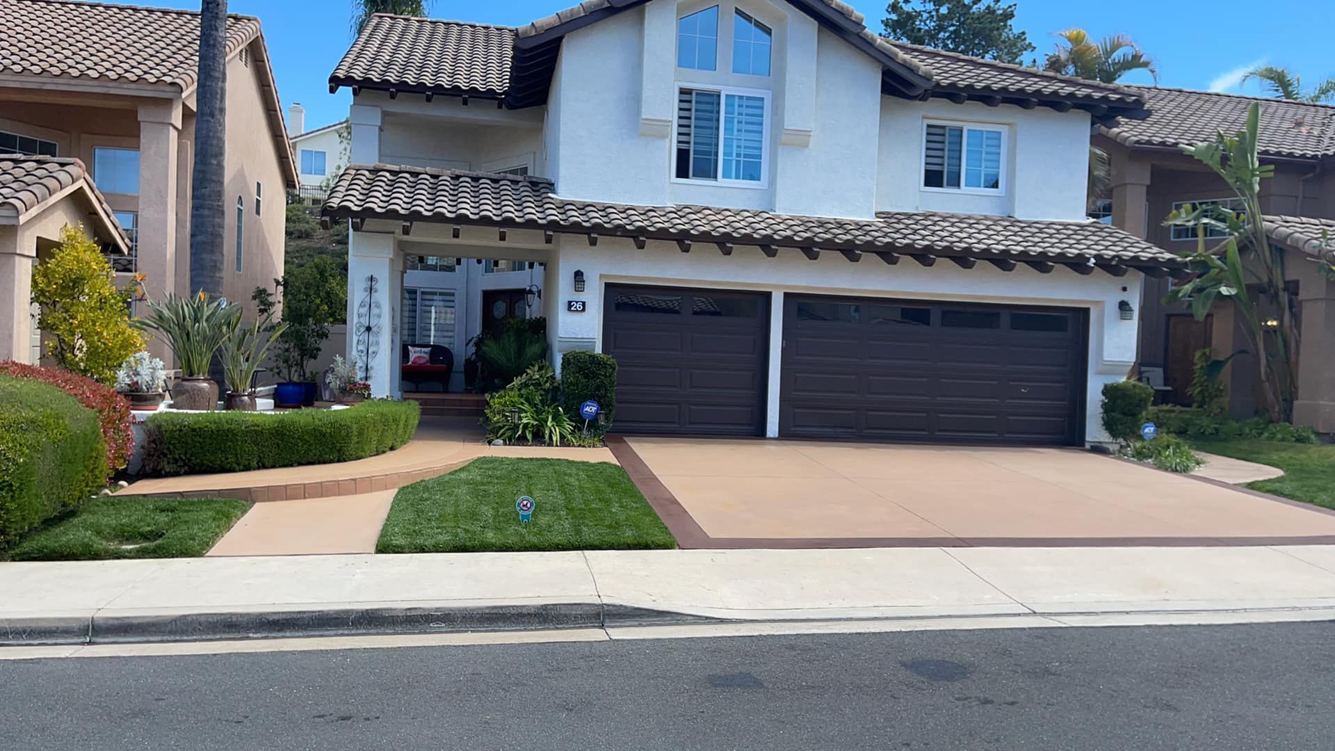 Two-story white house with brown garage doors, tiled roof, and green lawn.