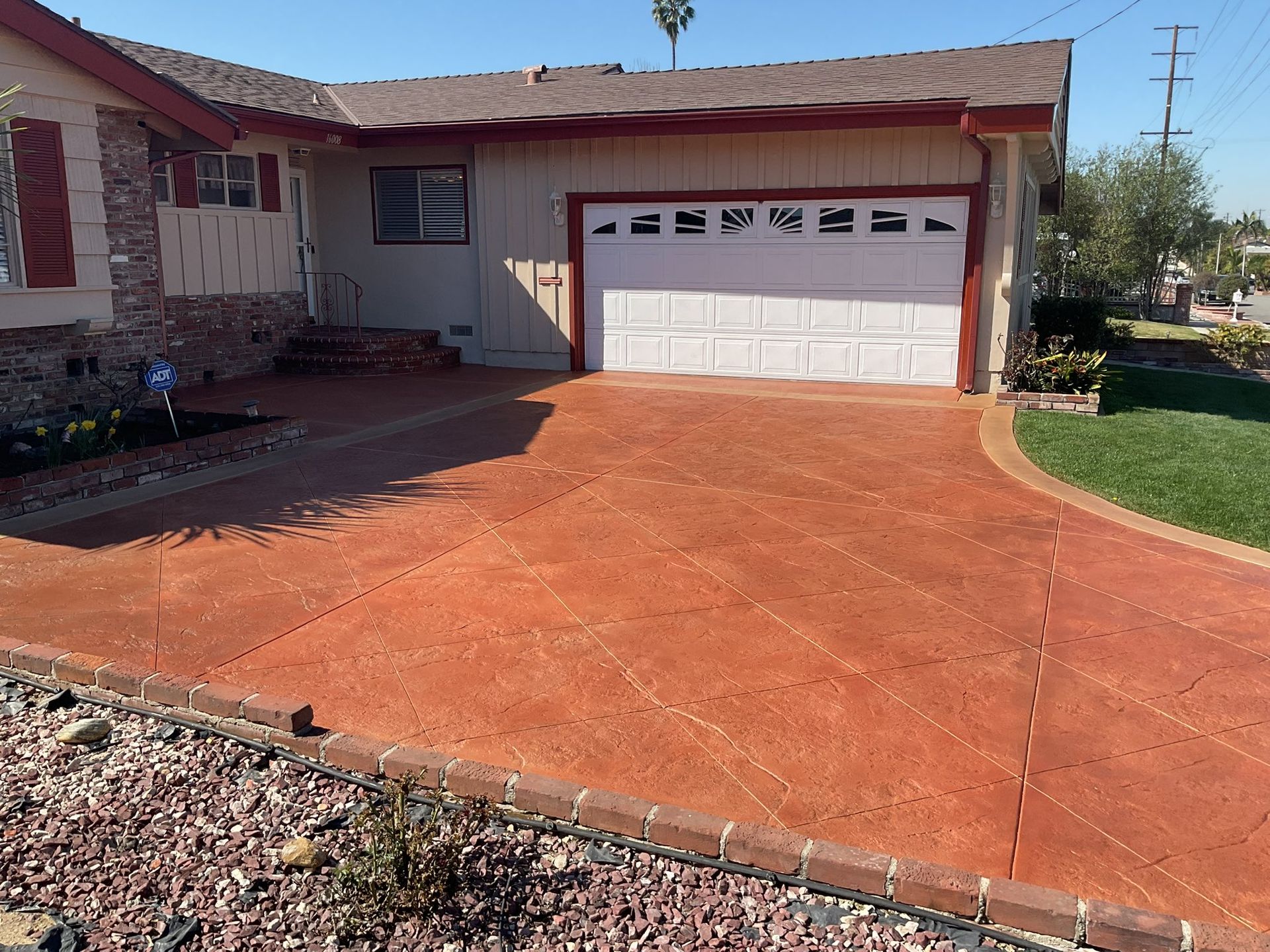 A house with an orange driveway, garage, and lawn in the daytime.