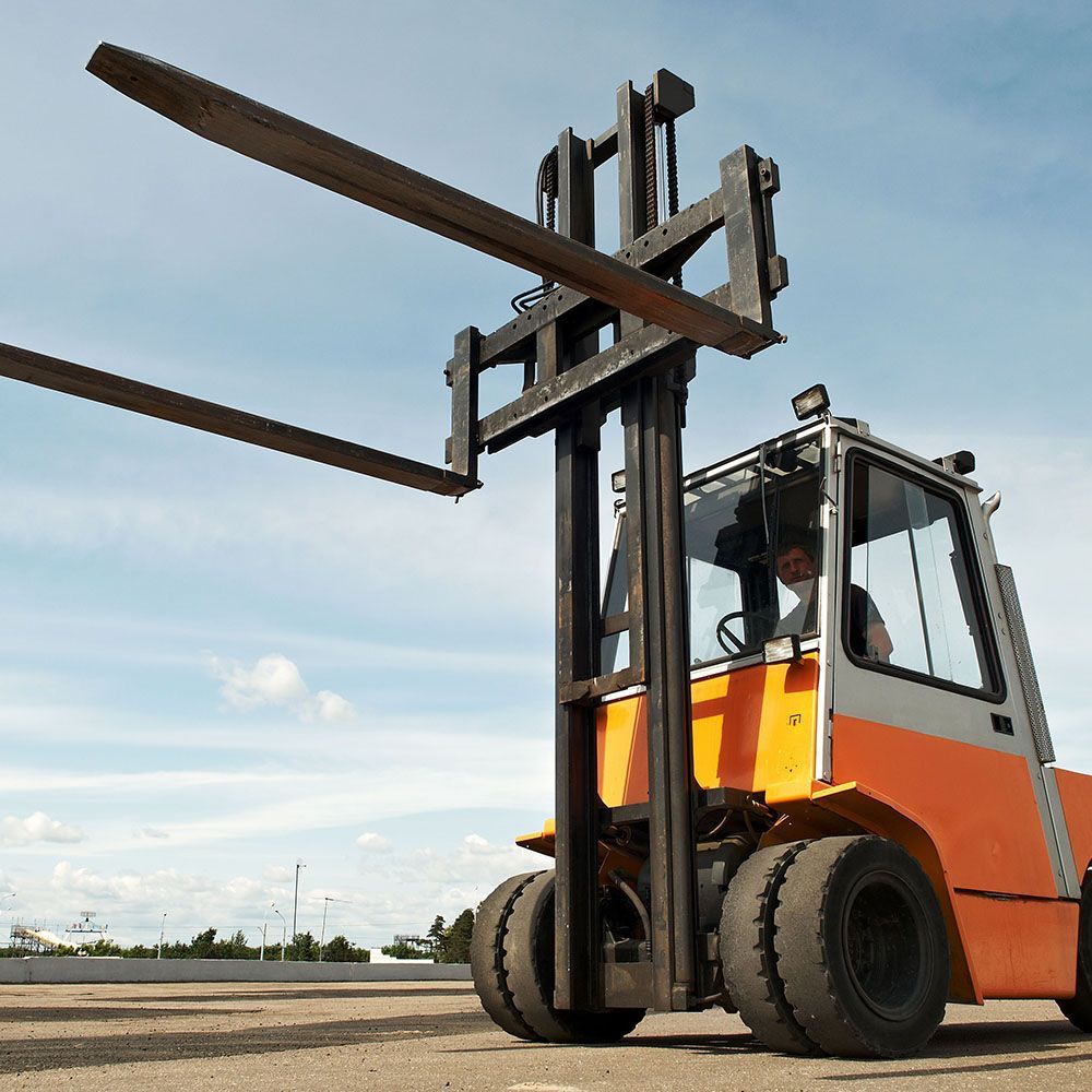 A man is driving a forklift with two forks on top of it