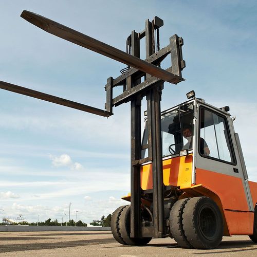 A man is driving a forklift with two forks on top of it
