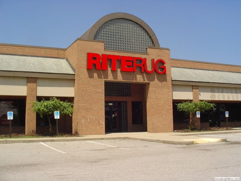 Riterug store exterior, red sign above the entrance, brick facade, sunny day.