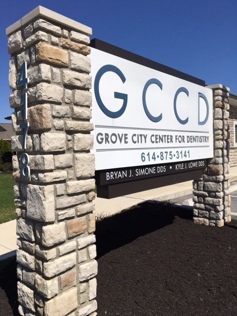 Sign for Grove City Center for Dentistry with stone columns. Text: GCCD, phone number, and dentist names.