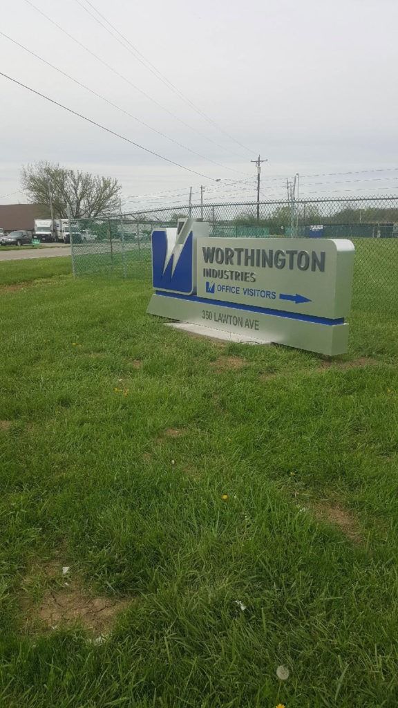 Sign for Worthington Steel with blue and silver accents on green grass.