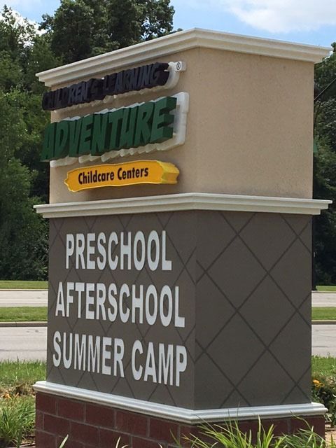 Sign for Adventure Childcare Centers: beige structure with green 