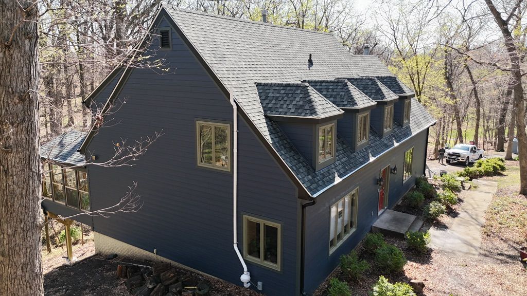 An aerial view of a large house in the middle of a forest.